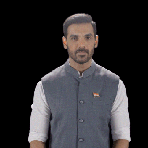 Celebrity gif. John Abraham, an Indian actor, smiles at us with charm and waves a hand in greeting.