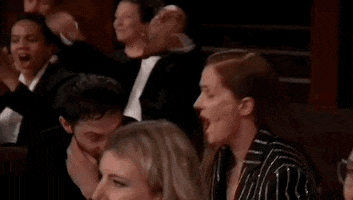 Oscars 2024 GIF. Justine Triet, at the Oscars, rises from her seat and hugs her partner Arthur Harari firmly, as he closes the embrace with pride and emotion.