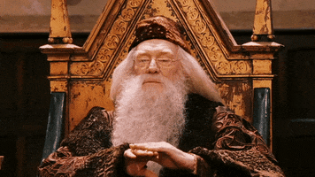 Movie gif. Richard Harris as Dumbledore from Harry Potter looks down at the hall of children with an almost bored expression on his face. He holds one hand out and pats it with his other hand as a way of clapping politely. 