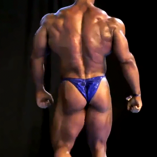 Video gif. The backside of an ultra-muscular male bodybuilder walking.