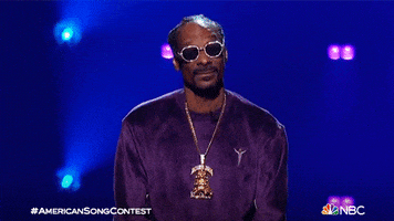 TV gif. Snoop Dogg as a host on American Song Contest looks at us and shrugs with both hands like he's out of answers.