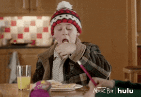 TV gif. David Rawle as Martin Moone on Moone Boy. He grabs a piece of toast from a plate and takes a big bite. He looks pleased with the flavor as he puts the toast back on the plate.