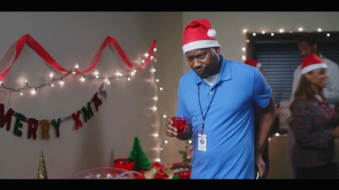 Muž s čepicí Santa Clause, nalévající si, tajně v kanceláři, na vánočním večírku, alkohol z placatky do kelímku. 
