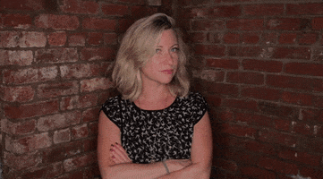 Video gif. A woman crosses her arms and glares at us with a side eye.