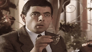 TV gif. In a sepia tone, a shocked and horrified Rowan Atkinson as Mr. Bean freezes, dropping his cup.