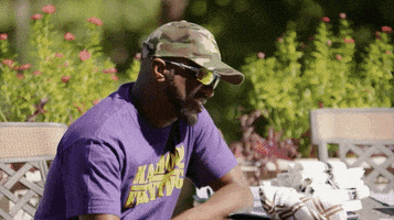 TV gif. Rickey Smiley as Pastor Rickey and Ajiona Alexus as DeAnna on the Rickey Smiley Show. They give each other a small smile and a high five as they chat next to each other at a patio table.