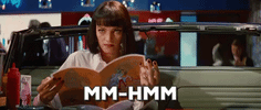 Movie gif. Uma Thurman, as Mia in Pulp Fiction, looks up from her diner menu and nods subtly.