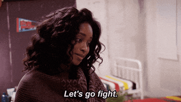 TV gif. In a scene from American Grit, a woman in a brown sweater looks downward right of frame as she speaks with low-key optimism. Text, "Let's go fight."