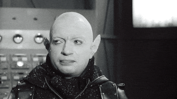 Video gif. Black and white footage of a bald man with pointed ears shaking his head firmly with a side eye.
