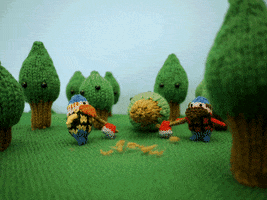 Stop-motion gif. Three-dimensional knitted scene of two lumberjacks in a forest of pine trees. They throw aside their axes, then hold hands, and walk out of the forest; a red heart appears in the sky over them.