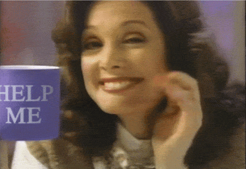 An animated gif of a woman looking and smiling at the camera, holding a coffee mug, but the coffee mug says "help me" on it.