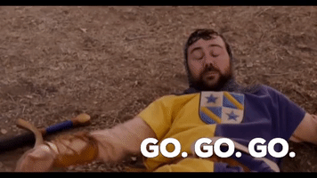 Movie gif. Joe Lo Truglio, as Kuzzik in Role Models, lying on the ground, lifting his head impatiently and saying "go, go, go."