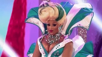 Reality TV gif. Peppermint from RuPaul's Drag Race gives a coy, faux look of pity touching their hands to their face.