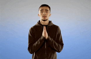 Video gif. Man looks at us with pleading eyes and shakes his praying hands. He then looks up towards the sky to continue praying.
