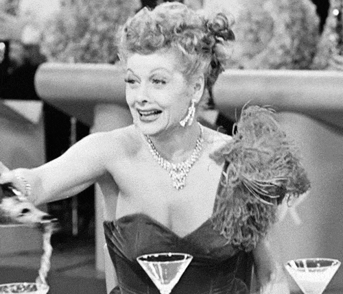 Černobílý pohyblivý obrázek se ženou ve společenských šatech nalévající šampaňské. 