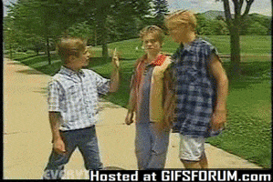 Video gif. Young boy is pointing his finger at a taller boy and the taller boy grabs his hand while taunting him. The younger boy winds up and slaps the taller boy and a "SLAP!" sticker appears.