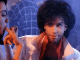 Celebrity gif. Prince in the New Power Generation music video moves a teacup c\up to his mouth to take a sip, but then pauses. He looks as if he’s surprised as he blinks and jerks his head a bit. 