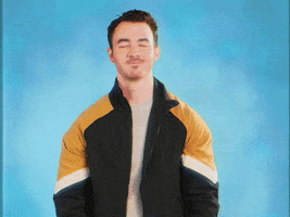Celebrity gif. Kevin Jonas, against a blue background, smirks at us and golf claps.