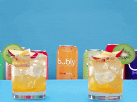 Digital art gif. In front of several bouncing cans of Bubly, two iced cocktail glasses topped with kiwi and apple slices float up and tap against each other. Text, "Cheers!" 