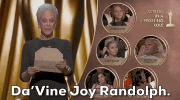 Oscars 2024 gif. Jamie Lee Curtis proudly reads, "Da'Vine Joy Randolph" from the award envelope. We zoom in on Randolph's tearful reaction, as she starts to cry while standing up to receive her award. 