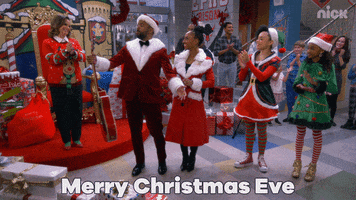 TV gif. Characters of That Girl Lay Lay in Christmas outfits, in a Christmas village set, clapping. Text, "Merry Christmas Eve."