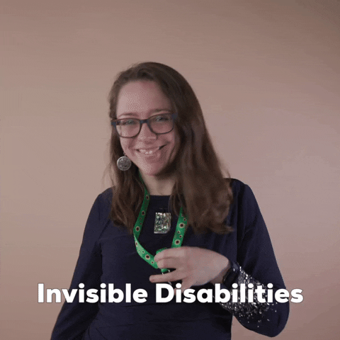 Reaction gif. A Disabled Latina woman with brown wavy hair and glasses shows off her green lanyard, presenting it with a toss and a smile. Text, "Invisible disabilities."