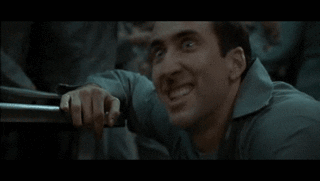 Movie gif. Nicolas Cage in The Death of Superman Lives: What Happened? shakes as he grins maniacally. 