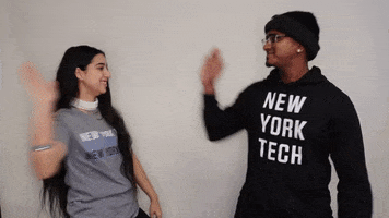 Video gif. Woman and man high five and look at us, smiling and nodding. They both wear New York Tech apparel.