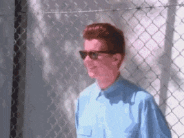 Celebrity gif. Musician Rick Astley dances to Never Going to Give You Up in shades and head-to-toe denim. 