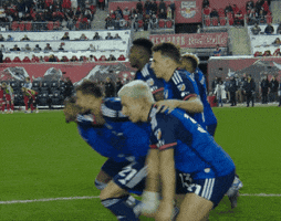 Sports gif. Álvaro Martín Barreal, a soccer player from FC Cincinnati raises his hands over his head, doing a wide spin and ending in a hug to one of his teammates. Other players go wild and run full speed across the field. 