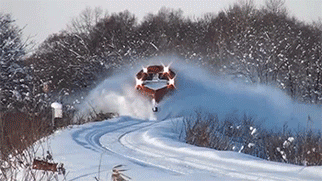 Video gif. Train equipped with snow plows rolls down a snow-covered track, pushing all the snow out of its way and leaving behind a cloud-like trail of snow in the air.
