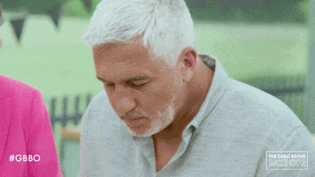 Reality TV gif. Paul Hollywood on The Great British Bake Off wipes away the sweat on his forehead with his wrist.
