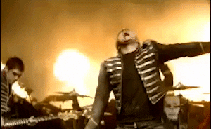 Music video gif. My Chemical Romance performs vigorously while flames blaze in the background of their video for Famous Last Words.