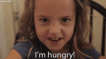 Video gif. A young girl looks  at us aggressively and says "I'm hungry!"