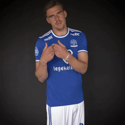 Sports gif. Kasper Jørgensen, a soccer player, looks unamused as he leans to the side and points down with both hands.