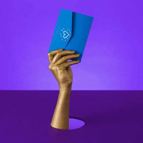 Video gif. On a purple background, a gold painted hand waves around a blue envelope with a heart drawn on it.