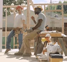 Deux ouvriers en bâtiments font une pause. L'un danse et l'autre mange en hochant la tête en rythme.