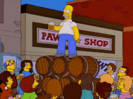 The Simpsons gif. Homer stands on top of a stack of wooden barrels, raising a mug of beer and leading an onlooking crowd in a toast. Text, "To alcohol! The cause of an solution to all of life's problems."