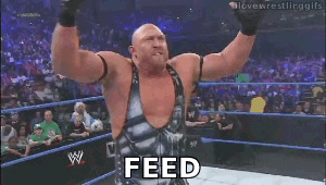 Sports gif. Buff wrestler in a gray and black singlet is angrily triumphant as he pumps his arm down and shouts to the entire arena, "FEED ME MORE!," which appears as text word by word.