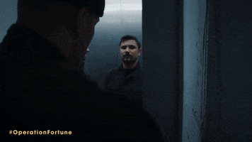 Movie gif. In a scene from Operation Fortune, two men wearing all black fight hand-to-hand in an elevator.