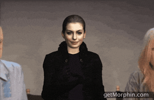 Digital art gif. Anne Hathaway is rendered as a 3D character, and she tosses gold confetti into the air.