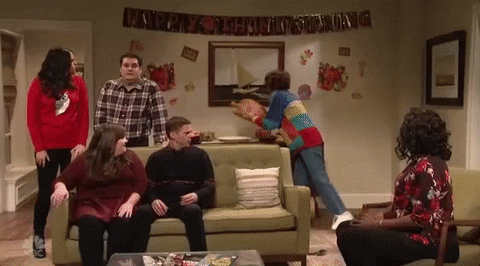 SNL gif. Kristen Wiig as Sue in a Thanksgiving skit rashly throws a whole turkey to break down a door and bolt through. The rest of the guests at the Thanksgiving party watch in absolute disbelief.