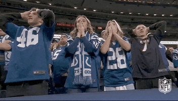Sports gif. A group of Indianapolis Colts fans watch the game from the sidelines. They're all wearing the team jersey and they're cheering for the Colts who seem to be winning, but all of a sudden, they fall onto their seats in despair, and all of them end up clutching their heads.