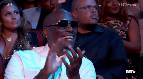 Celebrity gif. Tyrese Gibson is wearing sunglasses and clapping heavily while smiling at the BET Awards.
