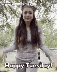 Video gif. Cheerful woman with long brown hair, magenta makeup, and dangling sun and moon earrings jumps in front of us and exclaims enthusiastically, "Happy Tuesday!," which appears as text.