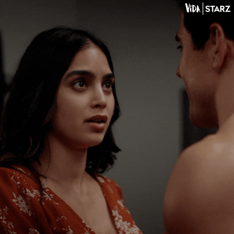 TV gif. Melissa Barrera as Lyn in Vida blinks in shock as she walks away from a man who stands shirtless in front of her. 