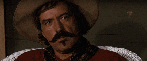 Video gif. A man with a handlebar mustache and a cowboy hat looks disinterested as he says, "Well. Bye."