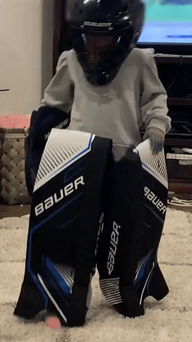 Little Girl Tries on Brother's Hockey Gear