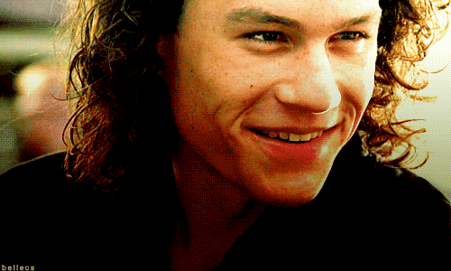 Celebrity gif. Heath Ledger gives a disarming smile as he winks saucily.