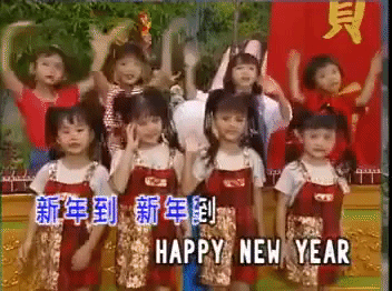 Video gif. A choir of little Taiwanese girls are performing for the new year, and they sing and dance a new year's song. They wave their arms and bounce back and forth while singing, "Gong Xi Fa Cai" in Chinese and "Happy New Year" in English.